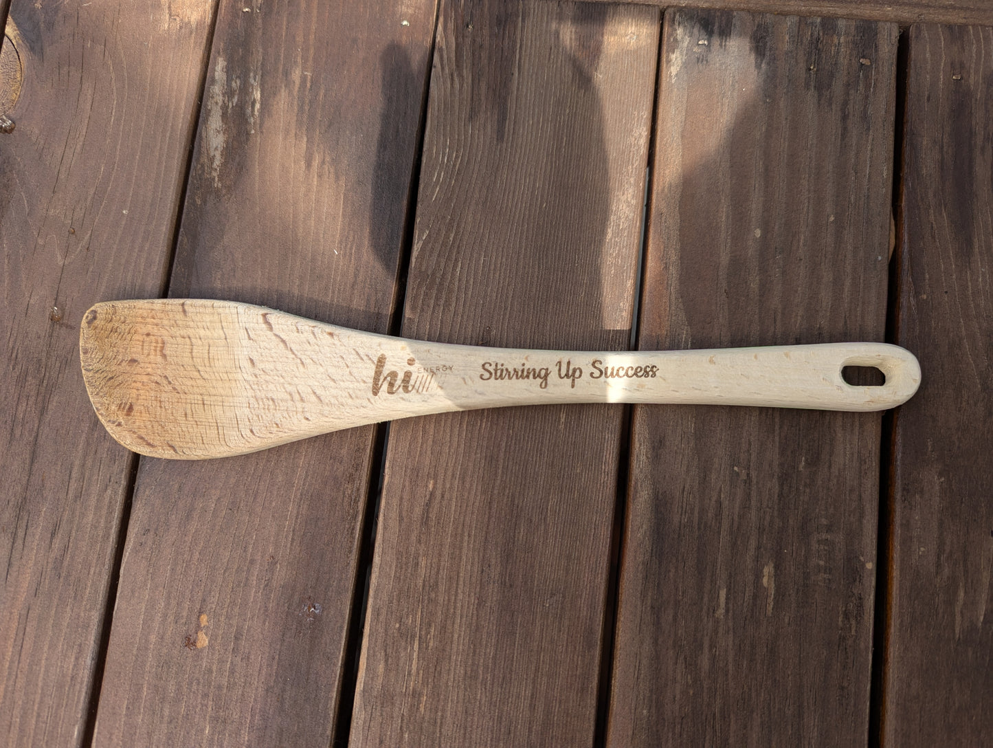 Wooden spoon with engraved text on a wooden surface