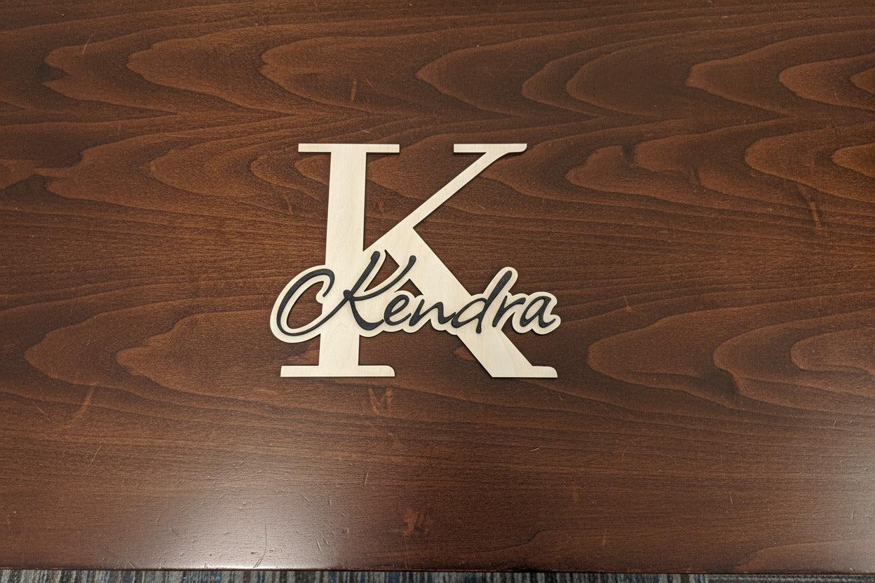 Wooden plaque with a large letter 'K' and the name 'Kendra' on a carpeted floor.