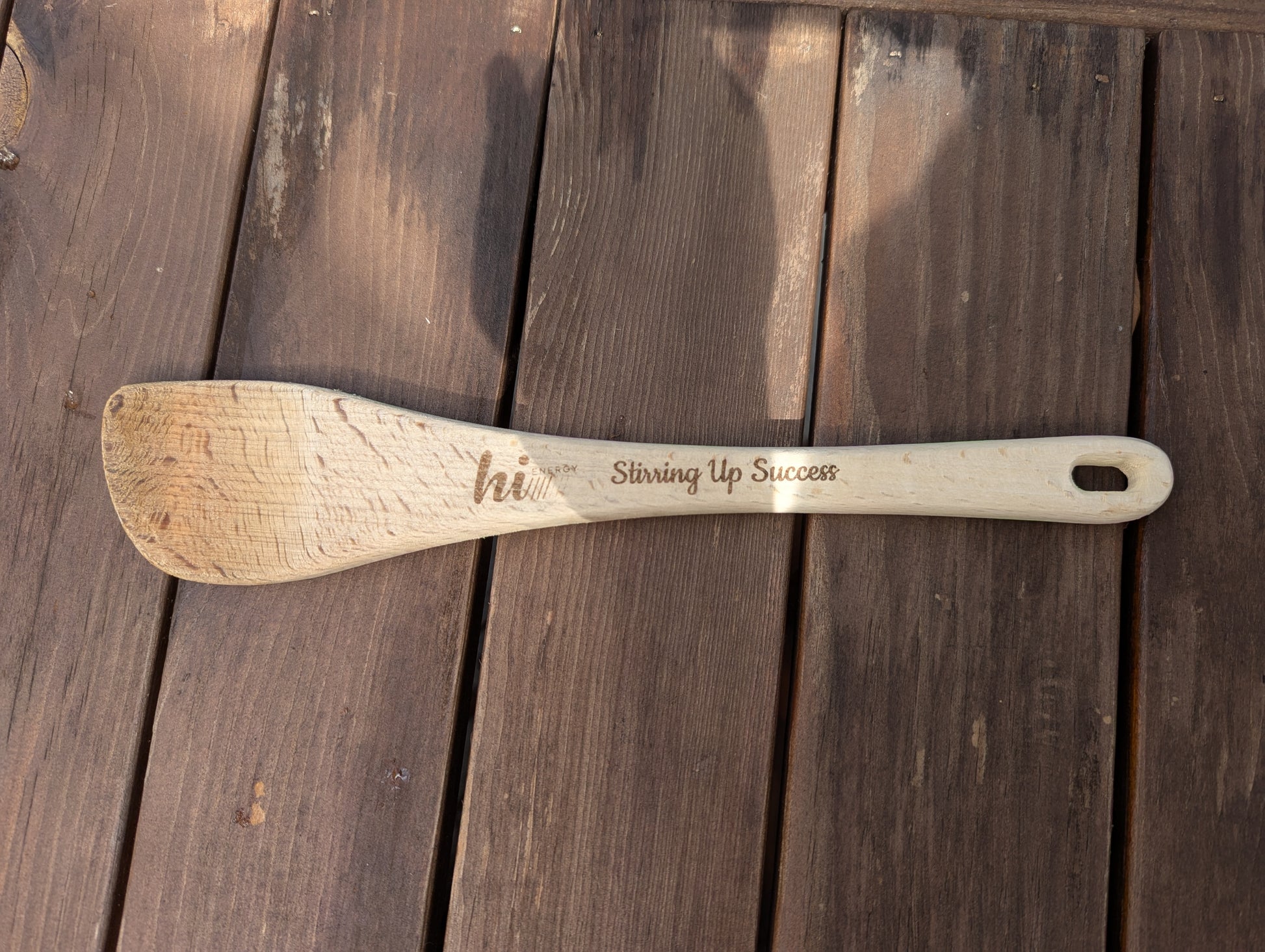 Wooden spoon with engraved text on a wooden surface