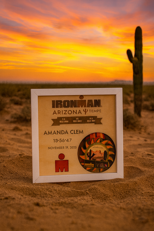 Framed Ironman Arizona race bib in front of a desert sunset with a cactus.