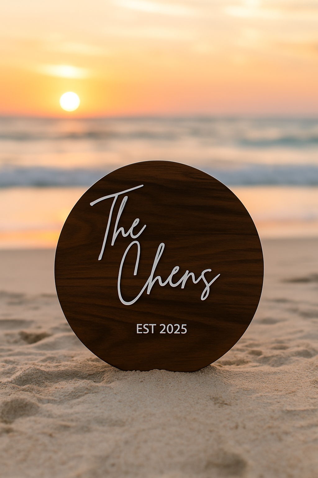 Round wooden sign with 'The Chens EST 2025' on a beach at sunset