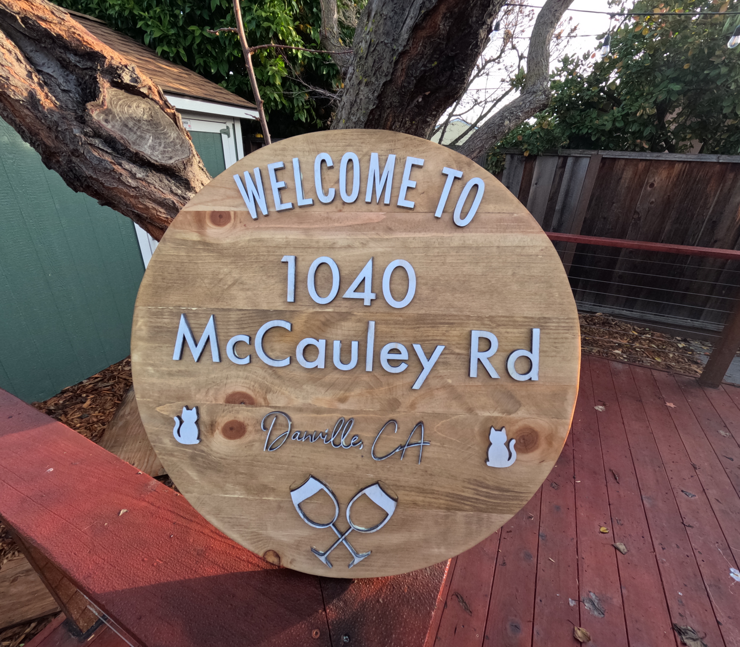 Wooden welcome sign with address and location details on a wooden deck.
